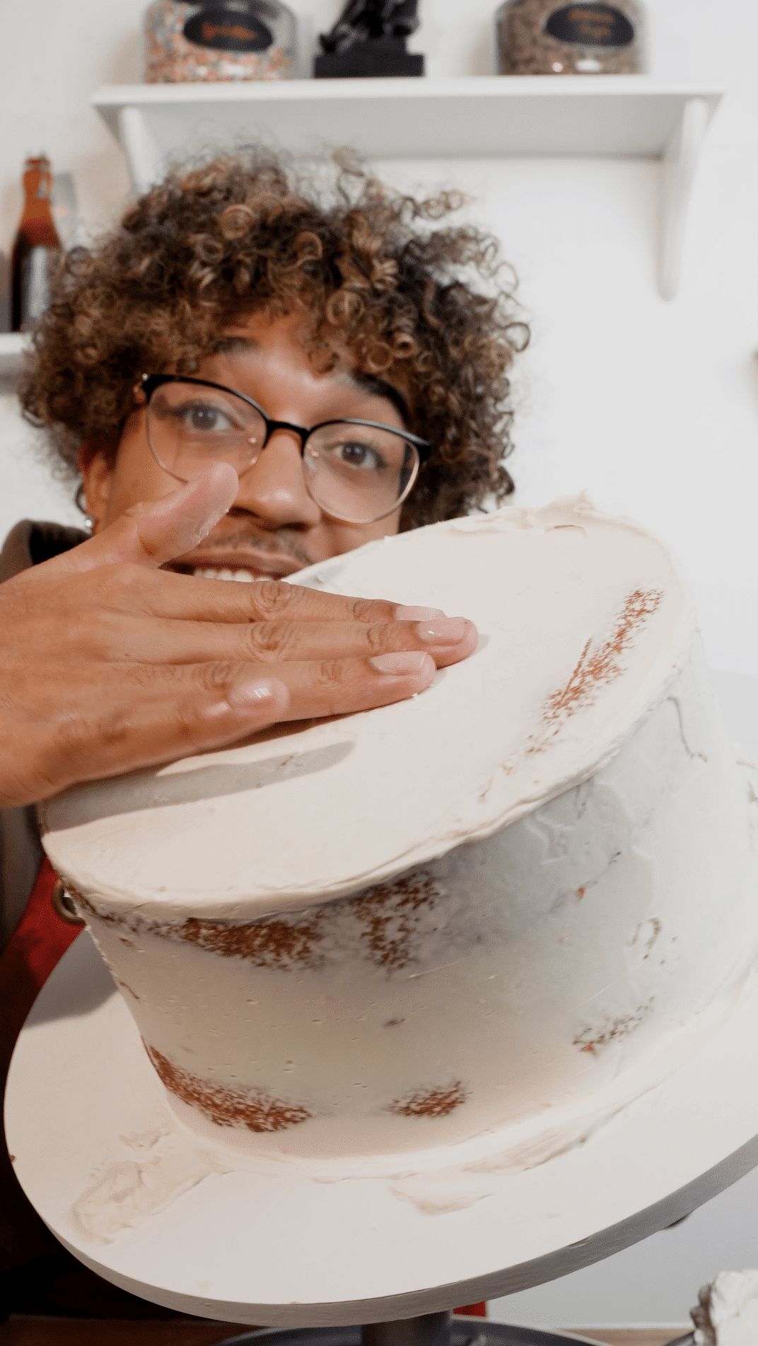 Baker holding a round cake layer with buttercream filling.